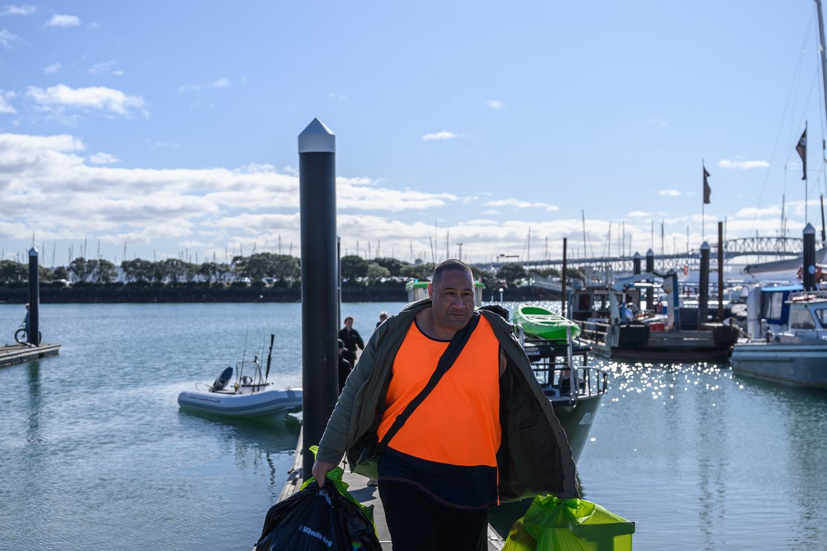 A crew member carrying bags of collected rubbish up the ramp