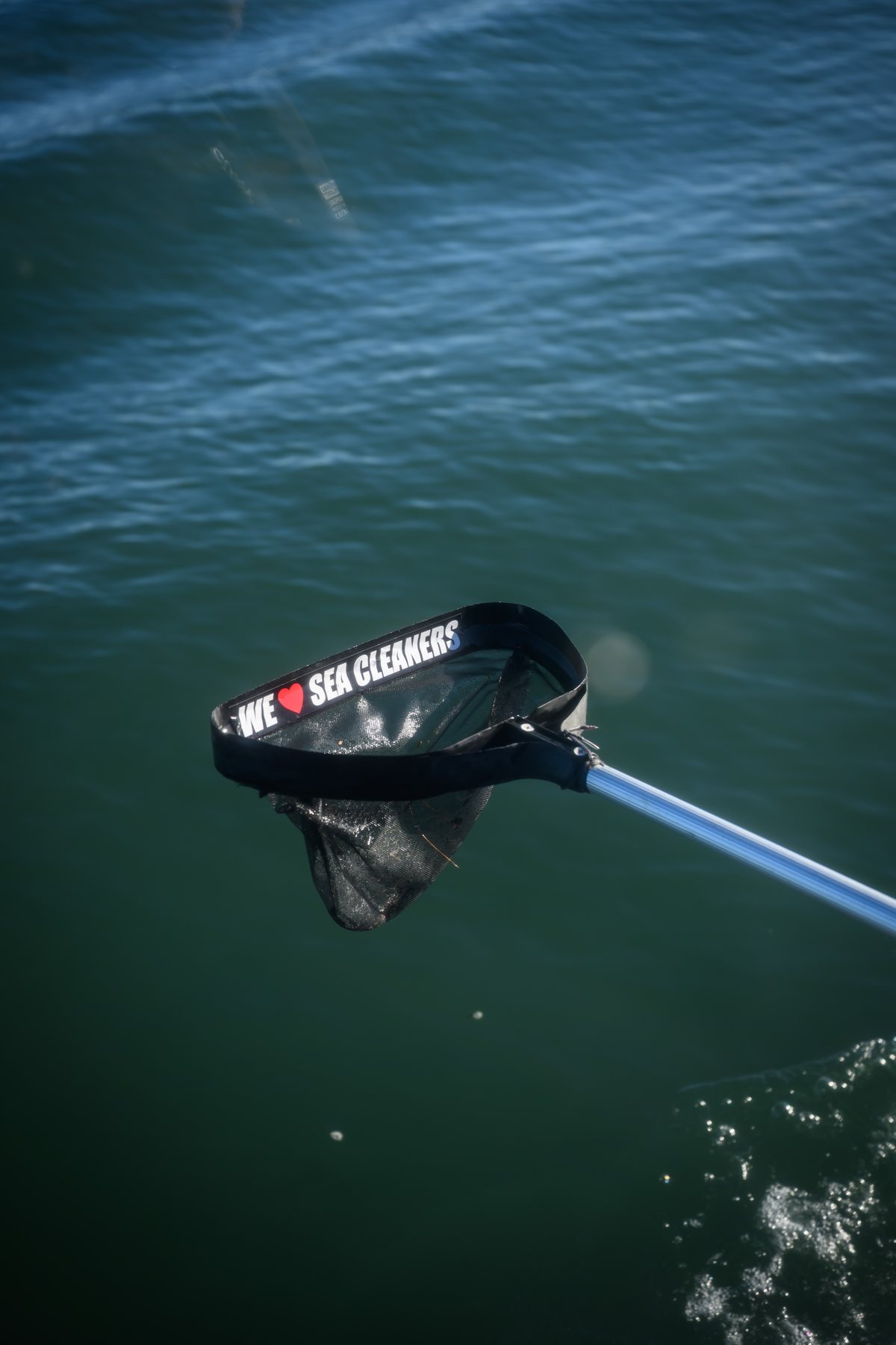 A Sea Cleaners scoop net lifting rubbish out of the harbour