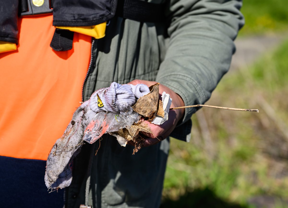Hands holding rubbish just pulled from the shoreline